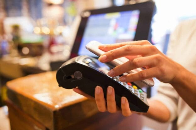 woman paying with nfc technology on mobile phone restaurant ca 34959179 1
