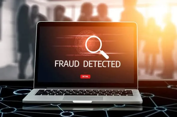 Fraud detection cybersecurity on laptop with magnifying glass icon.