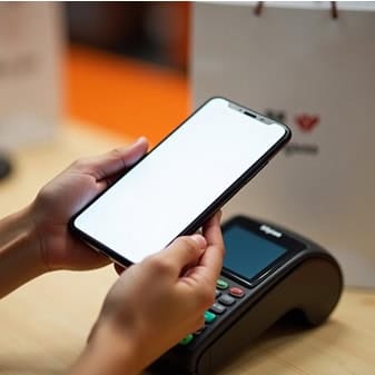 Close-up of person using mobile payment app on smartphone at point of sale terminal.