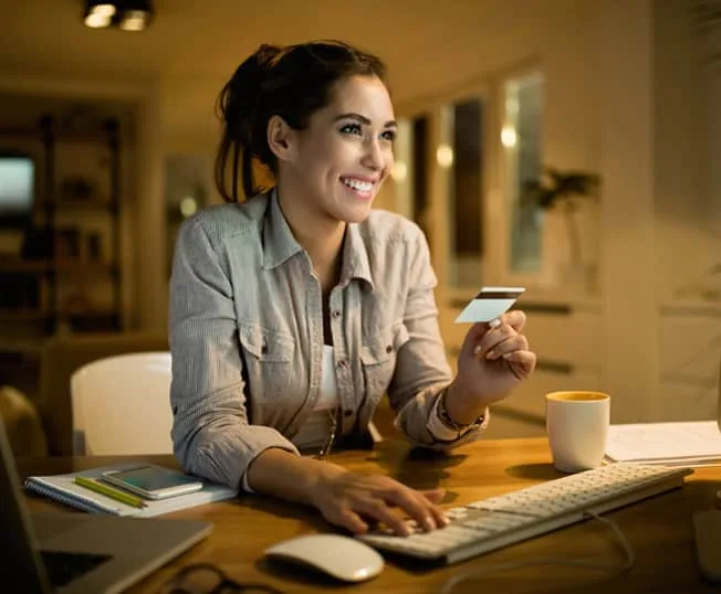 Customer using credit card at home for online shopping, payment processing, and secure transactions.