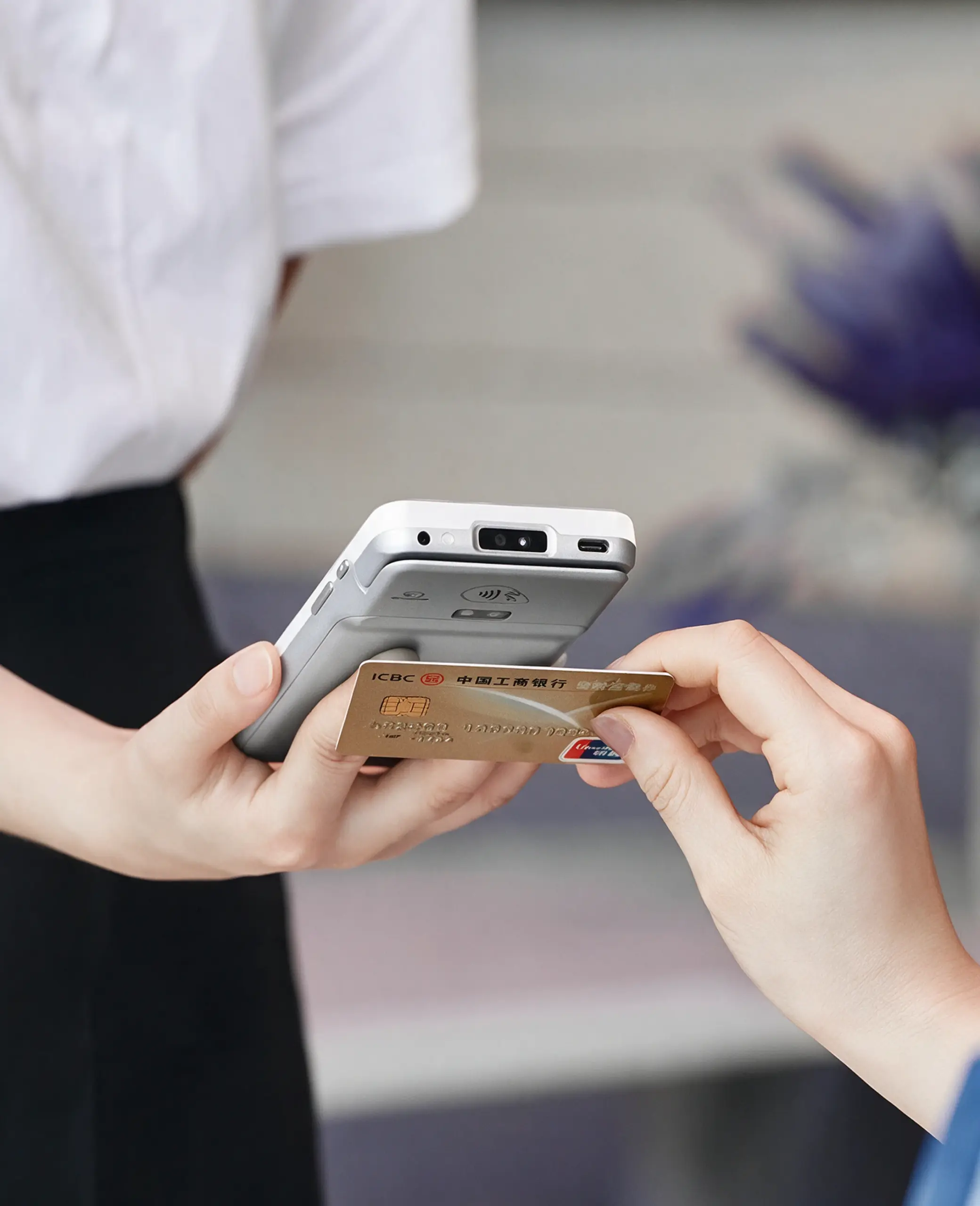 Customer presenting a payment card to a PAX A77 mobile payment terminal for secure in-person checkout