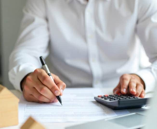 Simple business person using calculator and writing on documents for payment processing.