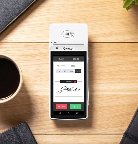 Contactless payment terminal for Host Merchant Services on wooden desk.