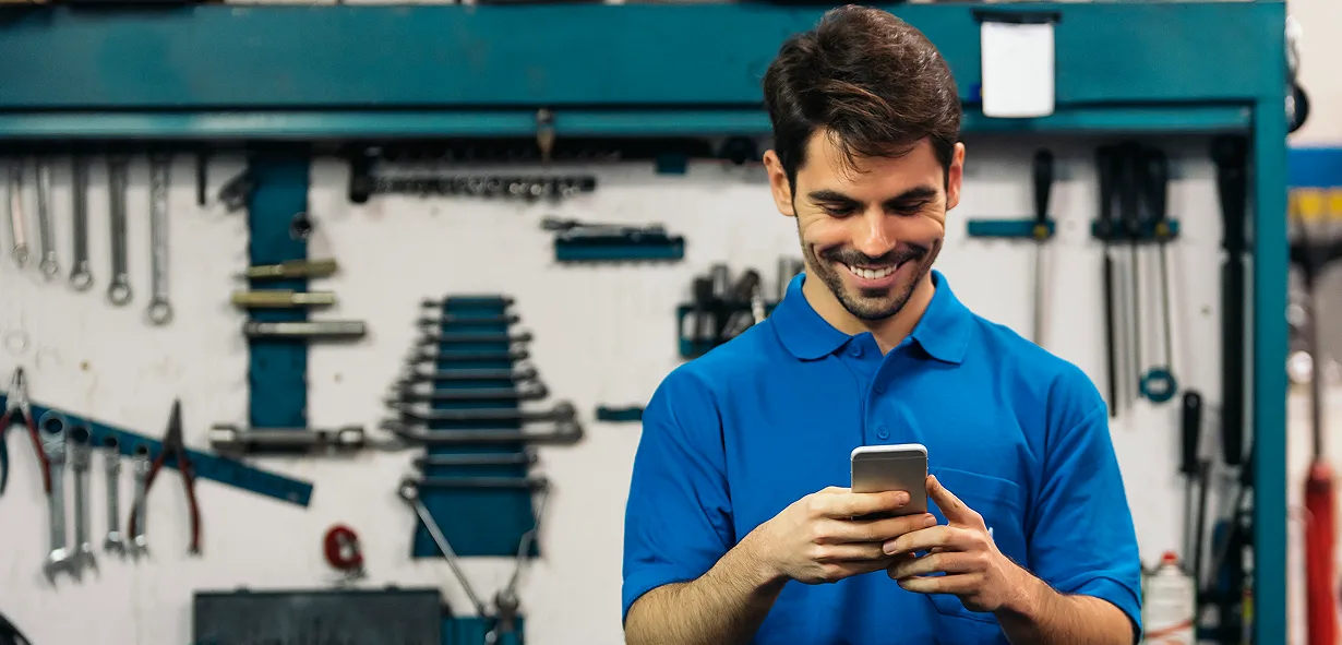 Mobile payment processing device used by a smiling worker in a car dealership.