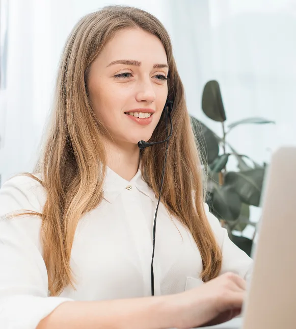 Customer support representative with headset working at computer for merchant service assistance.