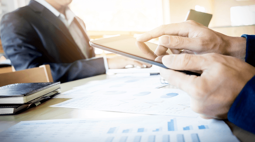 Business professionals signing a contract with financial charts on the desk, representing merchant services agreement.