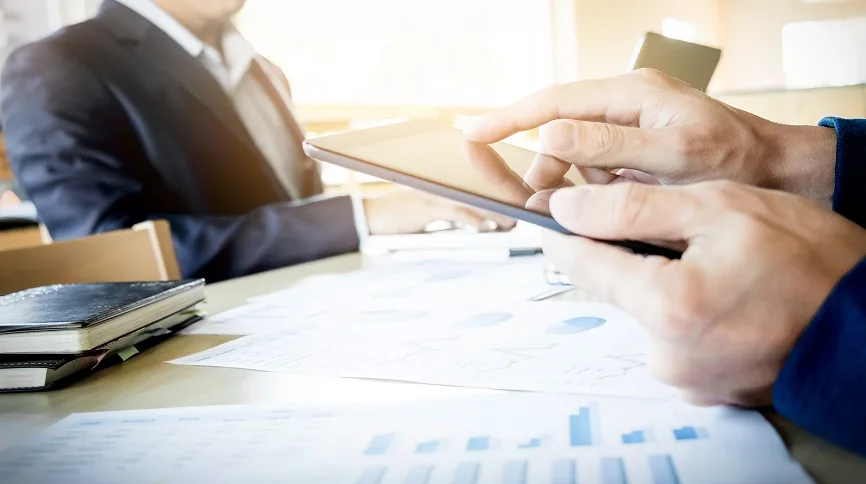 Business professionals signing a contract with financial charts on the desk, representing merchant services agreement.
