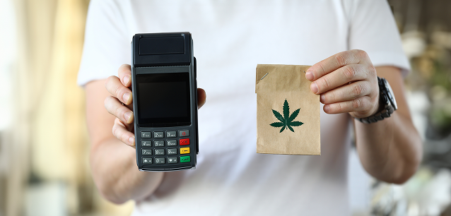 Black wallet on cash and cannabis buds, financial and legal considerations.