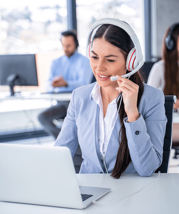 Professional customer support representative with headset working at laptop in office environment.