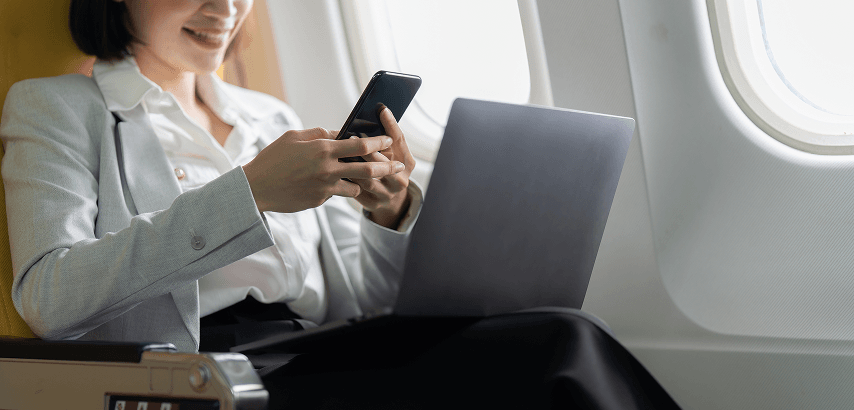 Businesswoman using a laptop on private jet for payment processing and merchant services.