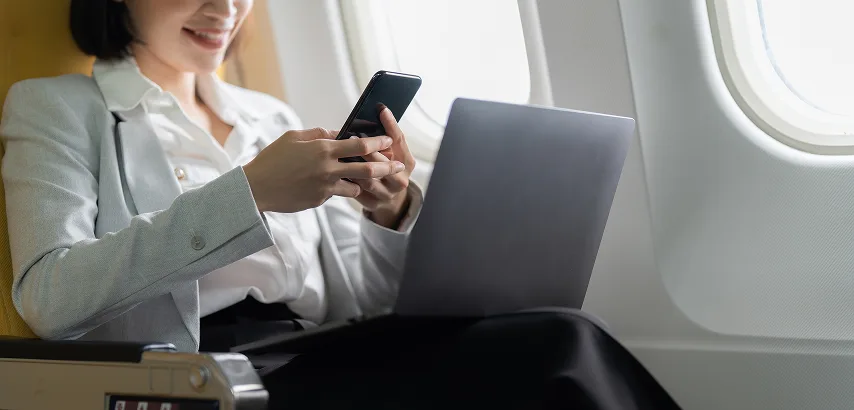 Businesswoman using a laptop on private jet for payment processing and merchant services.
