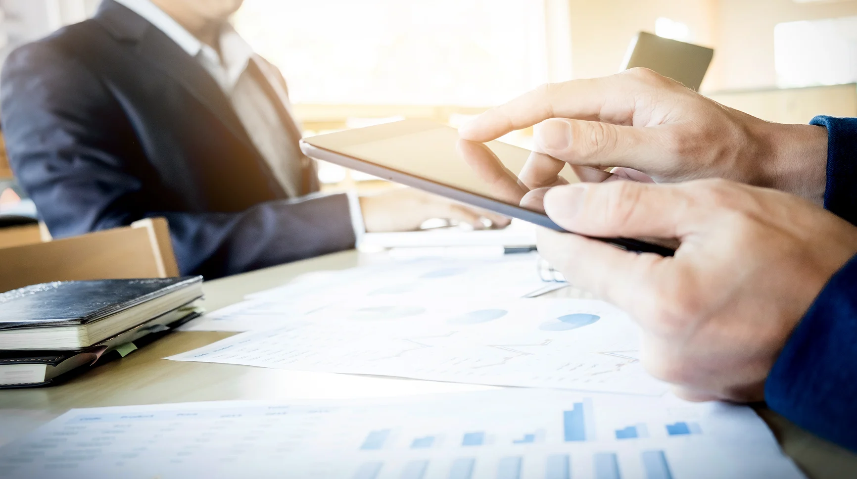 Business professionals signing a contract with financial charts on the desk, representing merchant services agreement.