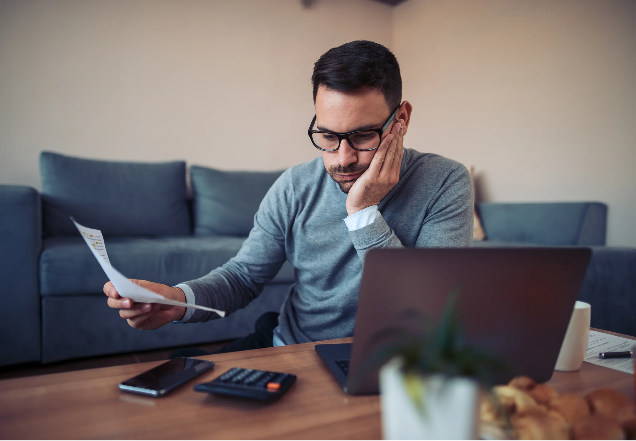 Merchant reviewing a Cayan account statement and payment fees while using a laptop and calculator