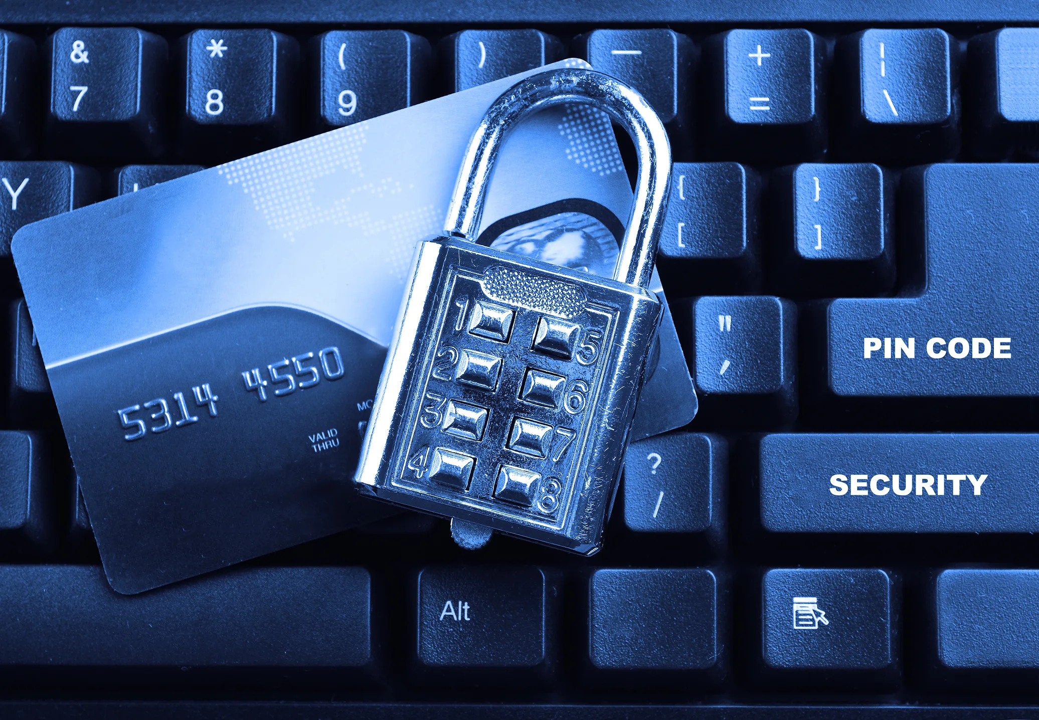Credit card secured with a padlock on a computer keyboard representing PCI compliance and payment data security