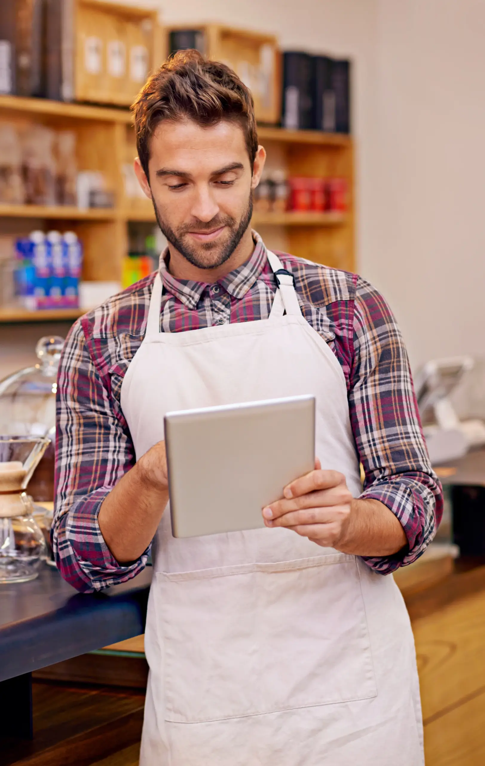 Small business owner using a tablet inside a retail store to manage daily operations and explore KORONA POS solutions