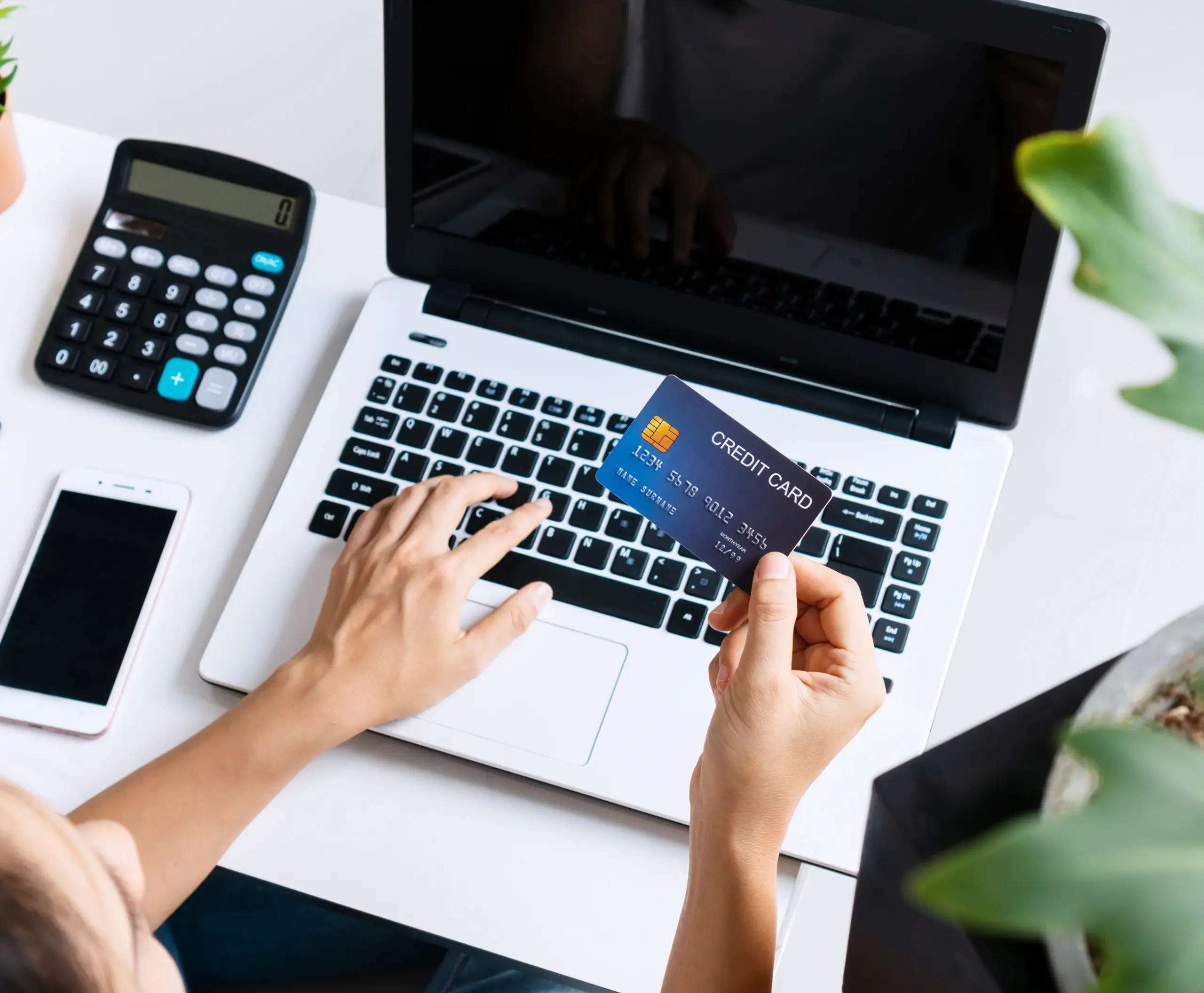 Business owner holding a credit card while using a laptop for online payment processing and financial management