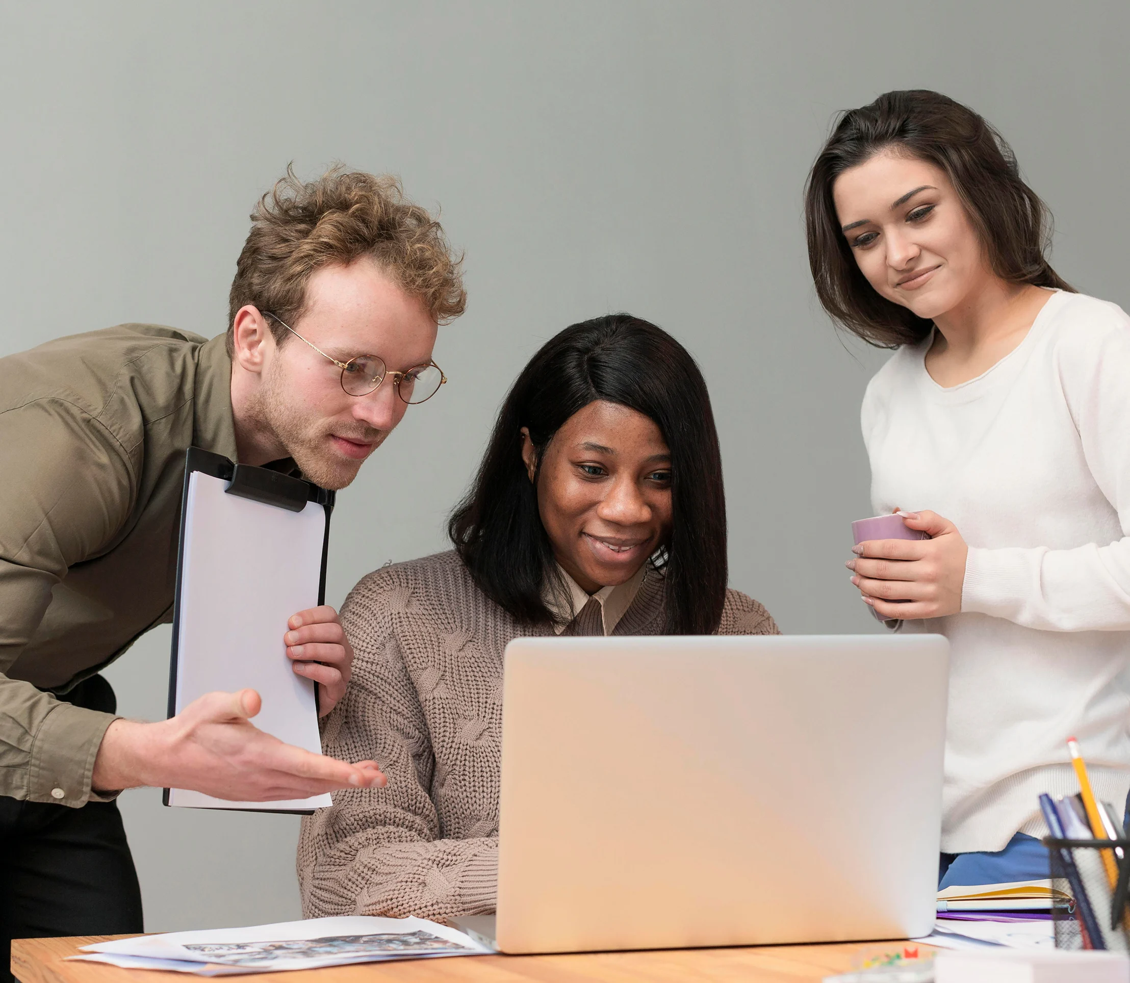 Three business professionals collaborating around a laptop to explore small business payment processing and merchant services solutions