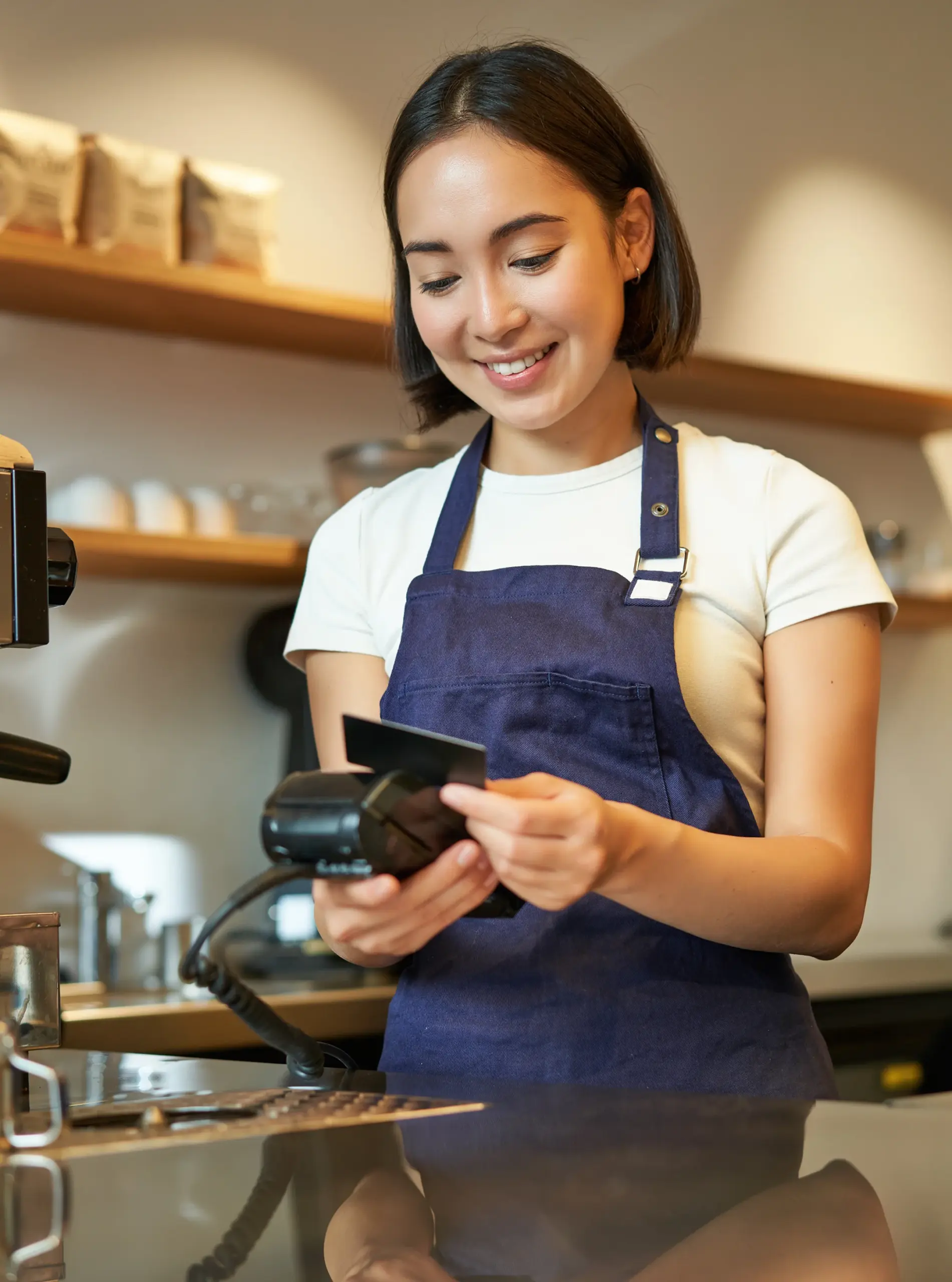 Small business owner accepting a card payment on a terminal at a café counter