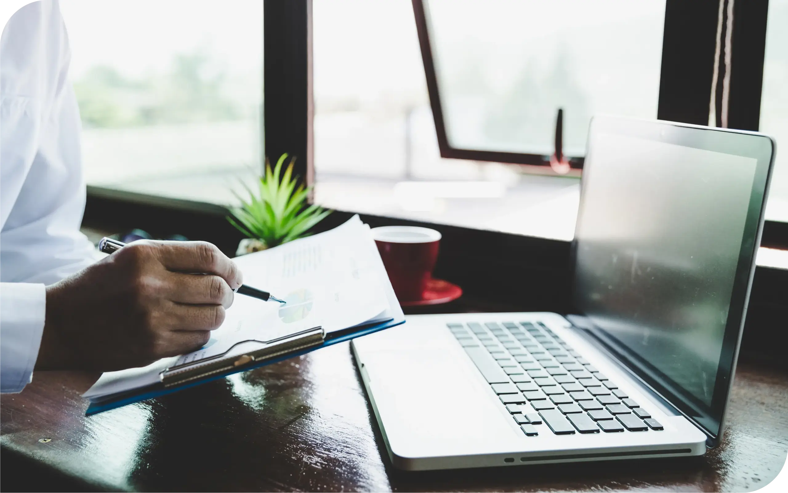 Business owner reviewing financial documents beside a laptop to prepare a credit repair merchant account application